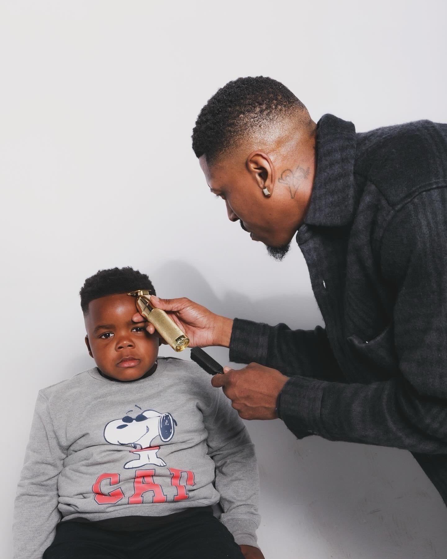 Fly lining up a young client against a white studio wall with a gold trimmer